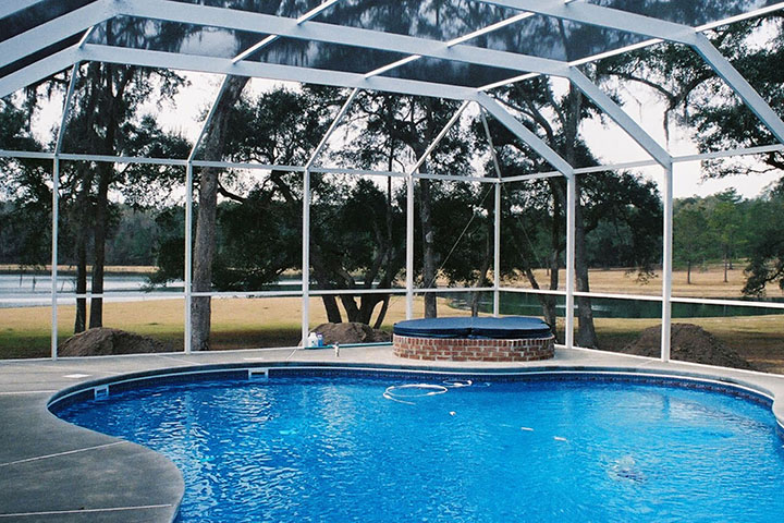 Screened backyard pool enclosure designed around an existing Southern Alabama home
